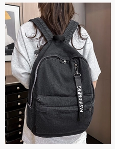 Detail of black denim backpack featuring high-capacity main pocket and fashion strap