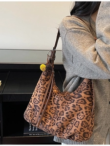 Fashionable leopard print hobo bag with tassel detail and pompom on a model