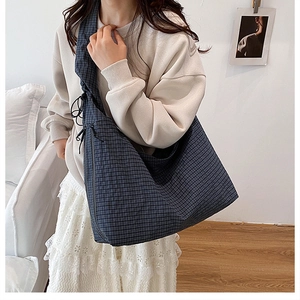 Detail of blue checkered tote bag showing the textured fabric and drawstring side detail