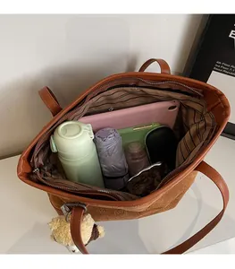 Top view of spacious brown tote bag interior holding a tablet, umbrella, and daily items