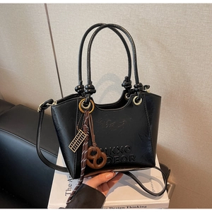 Detail of black pebbled leather bucket bag with embossed logo and golden abacus charm