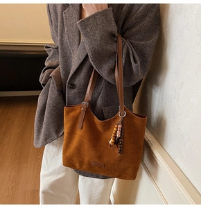 Gros plan d'un sac cabas en daim marron avec pompon en perles et bandoulières