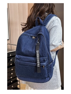 Detail view of large denim backpack in dark blue with decorative fashionbag strap