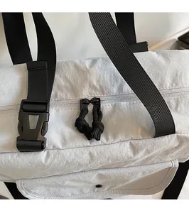 Detail of smooth metal zippers and plastic buckle on light grey nylon crossbody bag