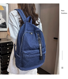 Detailed view of dark blue denim backpack with front zipper pocket and fashion webbing strap