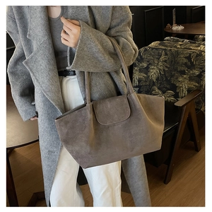 Detail of taupe suede tote bag styled with a grey coat for an elegant commuter look