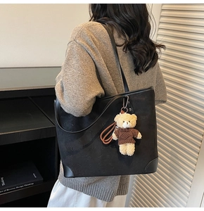 Detail of black embossed tote bag with teddy bear pendant and soft matte texture