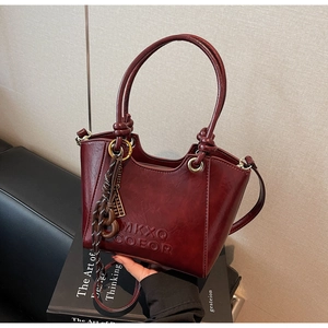 Detailed macro view of burgundy vintage leather bucket bag with embossed logo and metal rings