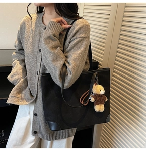 Detail of black tote bag with embossed star patterns and cute teddy bear pendant charm