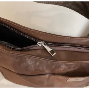 Close-up of smooth silver metal zipper and brown faux leather texture on tote bag