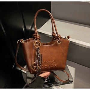 Detail of vintage brown leather handbag with embossed letters and knot handle decorations