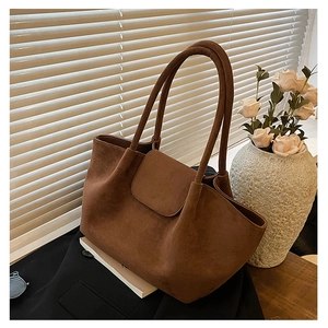Detailed macro view of brown suede tote bag featuring a practical flap cover design