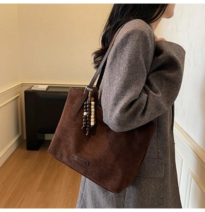 Détail du grand sac cabas en daim marron avec pompons en perles de bois et fini mat