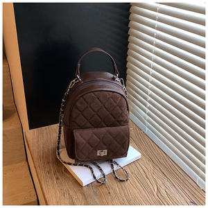 Détail d'un sac à dos matelassé marron foncé avec fermoir rotatif et bandoulière chaîne