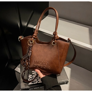 Close-up of vintage brown leather bucket bag with embossed logo and metal ring details