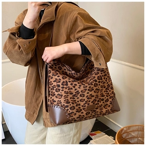 Detail of leopard print tote bag featuring brown leather patchwork and contrast stitching
