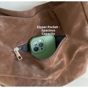 Detail view of large brown suede tote featuring an internal zipper pocket with a smartphone