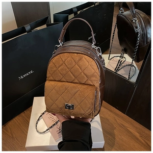 Détail d'un sac à dos matelassé marron avec fermoir tournant en métal et bandoulière