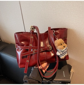Vue détaillée du sac cabas bordeaux en cuir verni avec boucles en métal et charm d'ours