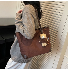 Detail of dark brown tote bag featuring bear embossing and a plush bear pendant
