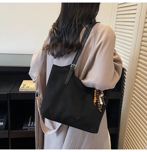 Détail d'un sac cabas noir avec pendentif perlé et bandoulière en cuir sur modèle