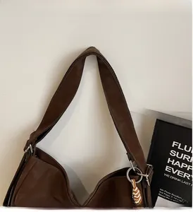 Close-up of wide brown leather strap and woven charm on a large canvas tote bag