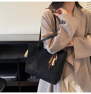 Détail du sac cabas noir en daim avec pendentif en perles de bois et bandoulière