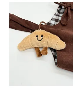 Détail d'un porte-clés en peluche croissant avec visage brodé sur un sac à main
