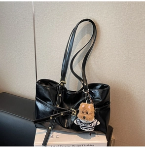 Détail du sac cabas en cuir ciré noir brillant avec boucle élégante et breloque chien