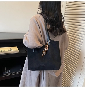 Détail du sac cabas en daim noir avec pendentif en perles de bois et fine bandoulière d'épaule