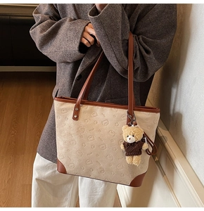 Detail view of canvas tote bag with brown leather trim and cute bear charm