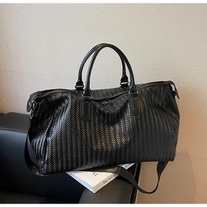 Detailed close-up of premium black woven faux leather texture on a spacious duffel bag