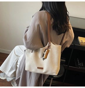 Détail du sac cabas couleur avoine avec fines anses marron et charme en perles de bois