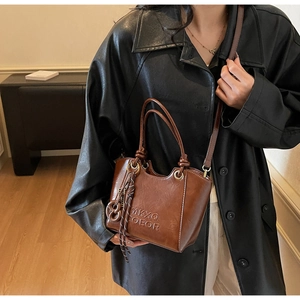 Close-up of vintage brown leather tote with MKXQ COEOR embossed logo and gold rings