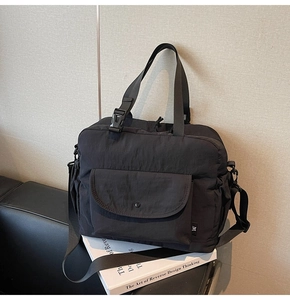 Detail of black multi-pocket commuter tote bag on a sofa with adjustable shoulder strap