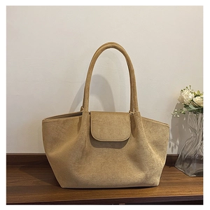 Macro shot of khaki suede tote bag texture and flap closure detail on the wooden table