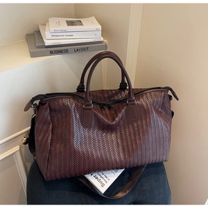 Macro view of woven chocolate brown travel bag with high-shine texture and straps