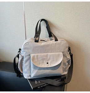 Detailed top view of light grey nylon crossbody bag with pockets on black leather background