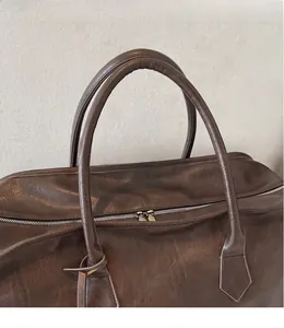 Détail d'un sac à main en cuir marron foncé avec fermetures éclair et poignée renforcée