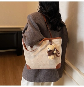 Close-up of vintage canvas tote bag with bear pattern and plush bear charm detail