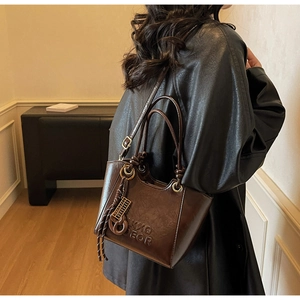 Detail of dark brown vintage leather bucket bag with embossed logo and metal hardware