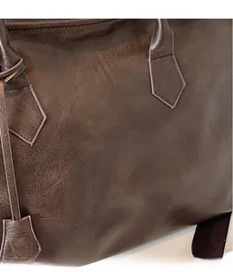 Gros plan sur la texture du cuir vintage marron foncé d'un sac à bandoulière