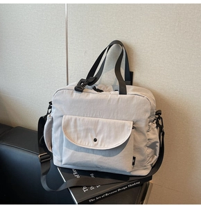 Detail of light gray nylon crossbody bag with large front pocket and buckle strap
