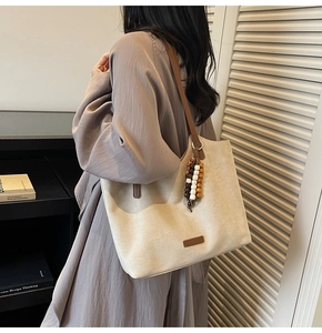 Détail du grand sac cabas en toile avec lanières en cuir marron et breloque en perles