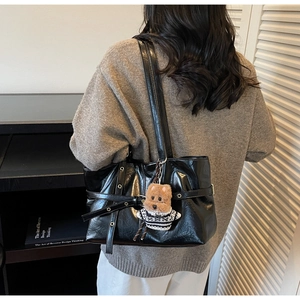 Détail du sac cabas en cuir ciré noir avec sangles à rivets et breloque chiot en peluche