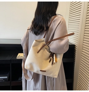 Détail du sac fourre-tout crème avec bandoulières marron et pompon en perles de bois