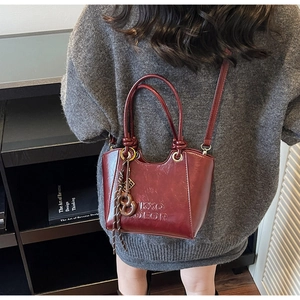 Detailed macro view of dark red glossy leather tote with tassel and embossed logo