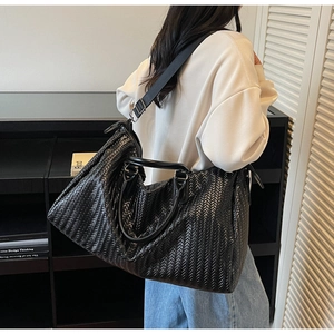 Detail of black woven texture gym bag with wide adjustable shoulder strap and leather handles