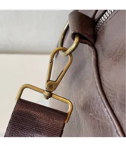 Gros plan du crochet en métal bronze antique et de la bandoulière en nylon du sac cuir