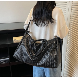 Detail of black woven leather handbag with herringbone pattern and detachable strap